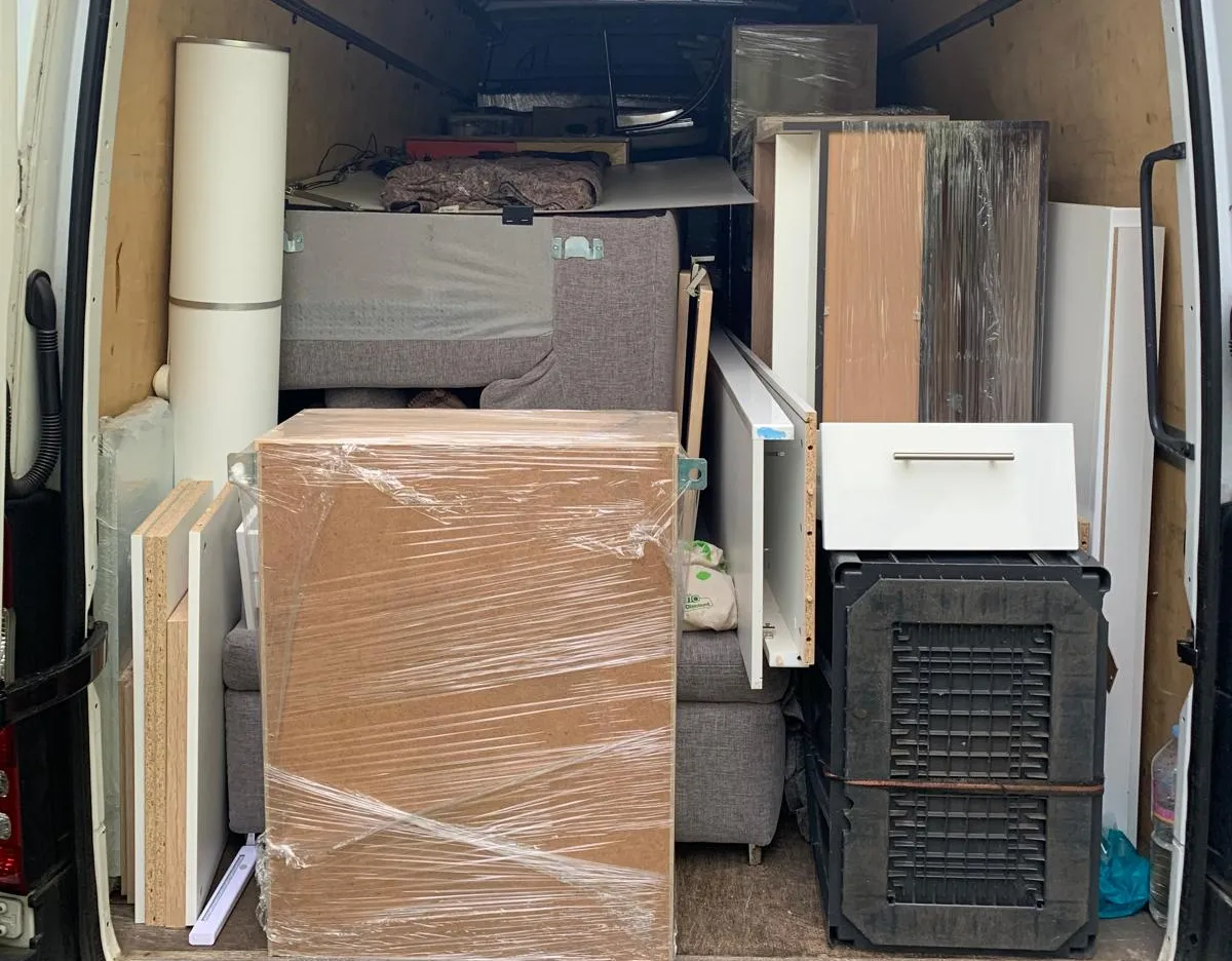 Vollgepackter Lieferwagen mit verpackten Möbelteilen und Polstermöbeln im Inneren.